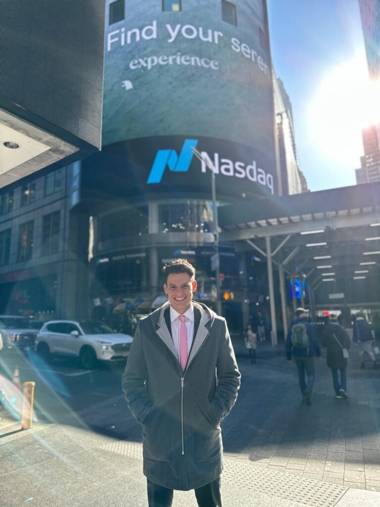 Man in a suit standing in front of the Nasdaq building